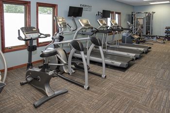 Fitness room with various cardio machines, wall mounted TV